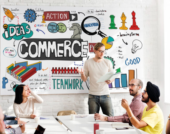 Photo of a startup with staff sitting down in front of a whiteboard talking about commerce and brainstorming.