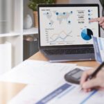 Business finance reporting papers and laptop showing charts and graphs representing Azure spend optimisation