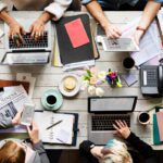 Aerial view of a business team having a meeting on a table to represent Outlook's scheduling poll