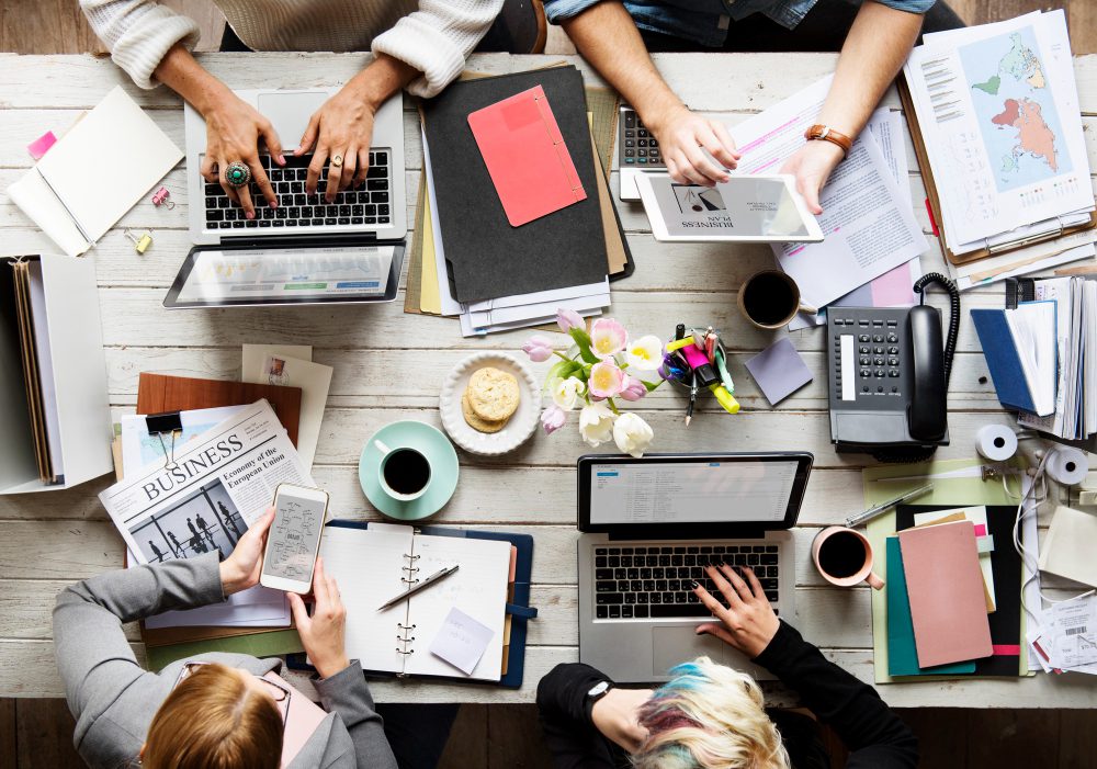 Aerial view of a business team having a meeting on a table to represent Outlook's scheduling poll
