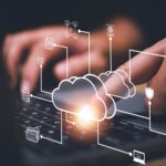 Cloud computing diagram overlaid on laptop typing to represent Boomi aXis connector for SAP