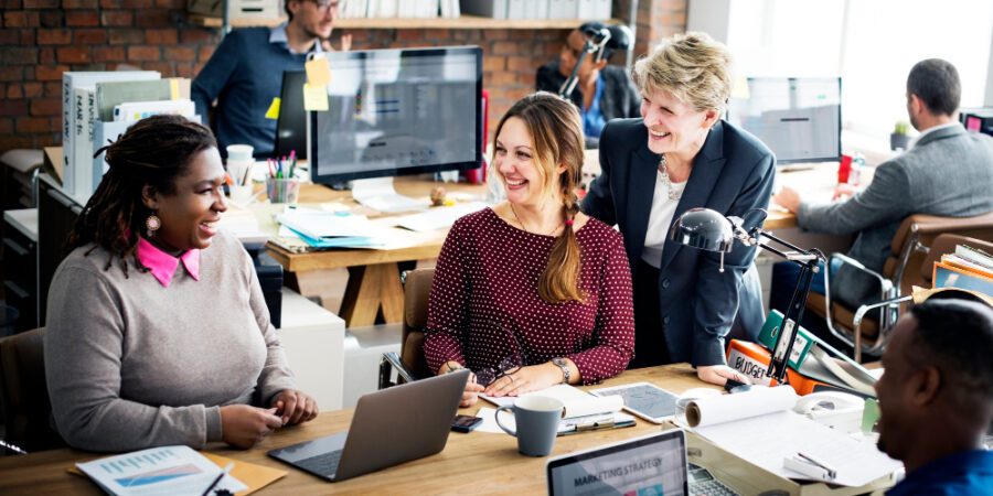 Colleagues in an office setting working happily together to represent SharePoint Modern Workplace